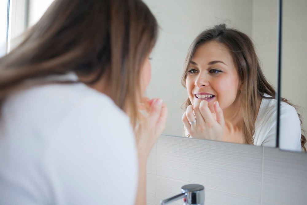 Woman checks her teeth in the mirror preventative dentistry Lansdale Pennsylvania